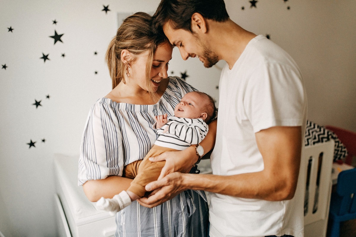 Loving parents cradle their precious newborn baby in a cozy and beautifully decorated nursery, surrounded by soft, pastel colours and warm natural light.